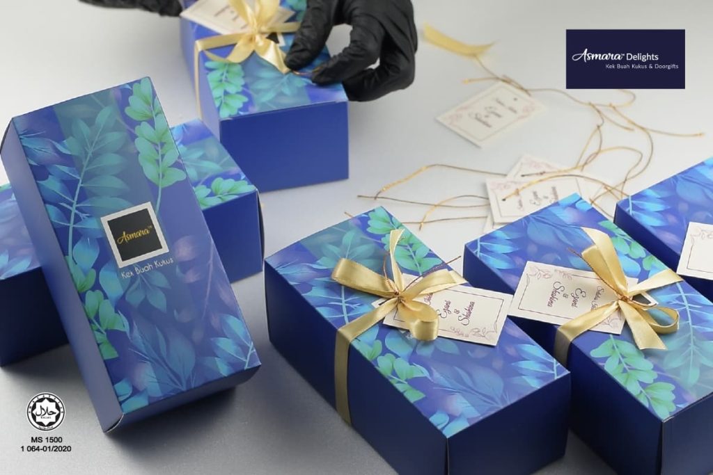 Exclusive doorgift boxes from Asmara Delights (kek buah kukus), wrapped in premium blue packaging with gold ribbons.